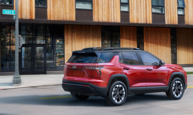 2027 Chevy Equinox driving past a wooden building